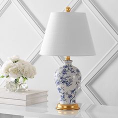 a blue and white vase sitting on top of a table next to a lamp