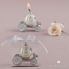 two small wedding carriage candles in a clear box with a white rose on the side