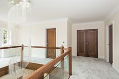 an empty room with a chandelier hanging from the ceiling and two wooden doors