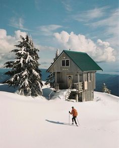 a person on skis in front of a small cabin