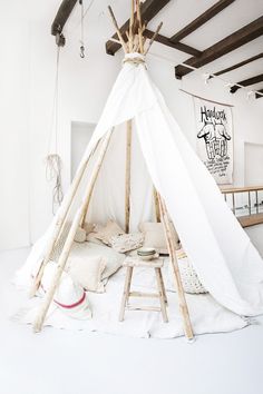 a teepee tent is set up in the middle of a room with white walls