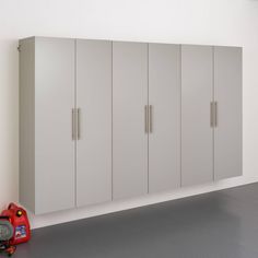 a room with several white cabinets and a red toy car on the floor next to it