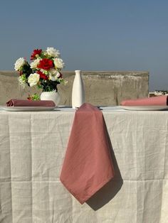 the table is set with pink napkins and white vase