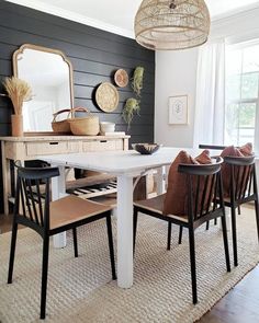 a dining room table with four chairs and a mirror on the wall in front of it