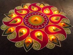 candles are lit in the shape of a flower on top of a circular design with leaves