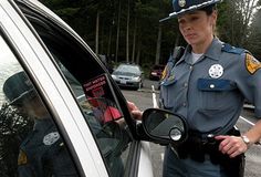 a woman police officer standing next to a car with her hand on the side mirror