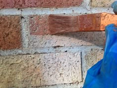 a blue bag is hanging on the side of a brick wall with a paintbrush in it