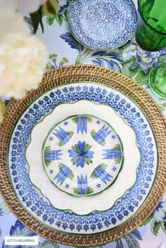 a blue and white plate sitting on top of a table next to a green vase