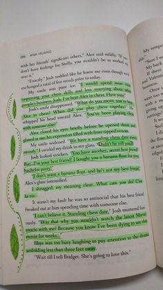 an open book with green writing on the page and two leaves drawn in each corner