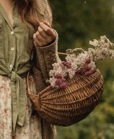 a woman holding a wicker basket with flowers in it