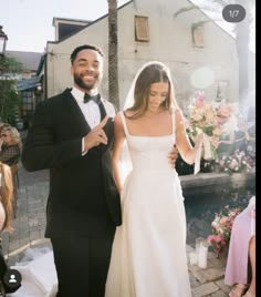 a man in a tuxedo and a woman in a wedding dress walking down the aisle