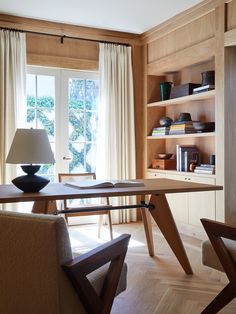 a living room filled with furniture next to a window covered in curtains and bookshelves