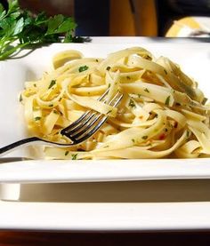 a white plate topped with pasta and garnished with parsley next to a fork