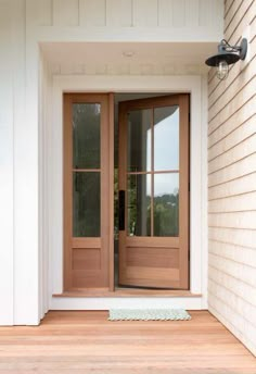 the front door of a house with two glass doors on each side and an entry mat