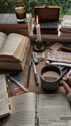 an open book on a table next to a cup of coffee and several other books