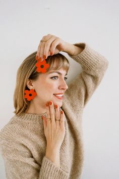 a woman with red flowers in her hair and wearing an orange flower clip on her head