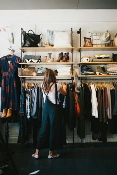 a woman standing in front of a rack of clothes