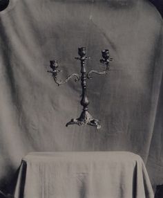 two candelabra lights sitting on top of a table with a cloth draped over it