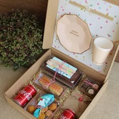 an open box filled with donuts and other treats next to a cup of coffee