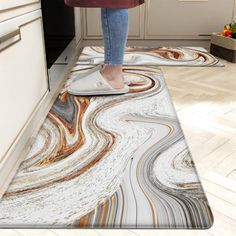 a woman standing on top of a kitchen floor next to an oven and countertop