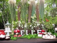 a table topped with lots of food covered in frosting next to plants and trees