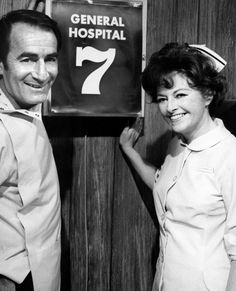 two people standing next to each other in front of a sign that says general hospital