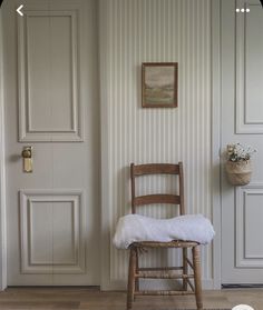 a wooden chair sitting in front of a white door