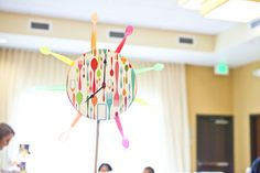 a clock made out of spoons and forks on top of a wooden table with people sitting around it