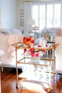 a living room filled with furniture and flowers on top of a glass table in front of a window