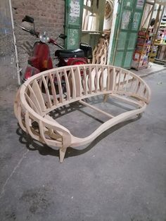 a motorcycle parked next to a building with a curved wooden bench on the ground in front of it