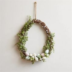 a wreath with eggs and greenery hanging on a wall