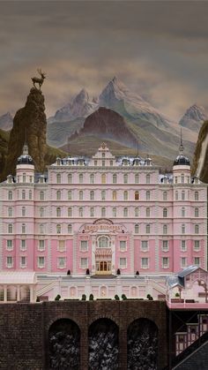 the grand hotel is pink and white with mountains in the backgroung behind it