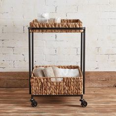 an iron and wicker shelf with two baskets on wheels