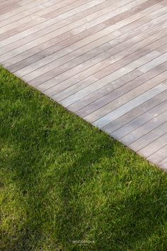 a man riding a skateboard down the side of a wooden walkway on top of green grass