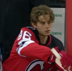 a young man in red jersey holding a hockey stick