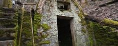 an old stone building with moss growing on the walls and steps leading up to it