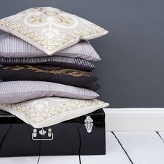 a stack of pillows sitting on top of a black suitcase next to a wall and floor