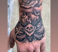 a man's hand with a skull and rose tattoo on it