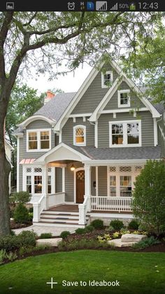 a gray house with white trim and two story windows on the second floor is surrounded by trees