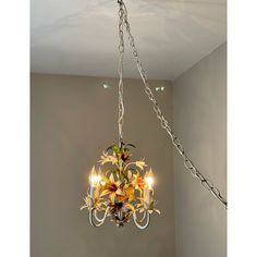 a chandelier with flowers hanging from it's sides in a room next to a wall