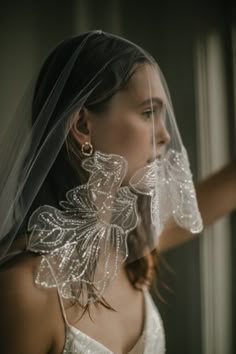 a woman wearing a wedding veil and earrings