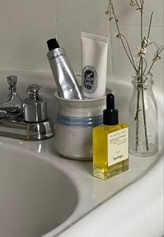 a white sink sitting next to a bath tub filled with personal care items