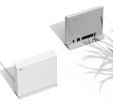 an electronic device sitting on top of a white surface next to a plant and another device