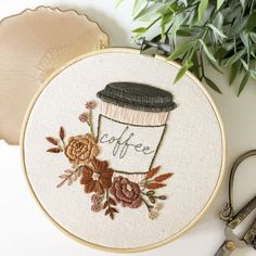 a coffee cup with the word coffee on it is surrounded by flowers and scissors next to a potted plant