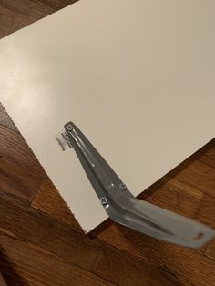 a pair of scissors laying on top of a piece of paper that is taped to the floor