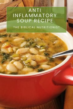 a red bowl filled with white beans and spinach next to bread on a table