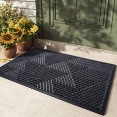 a black door mat on the ground with sunflowers