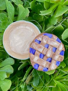 a blue and white plate sitting on top of green leaves next to a brown pie