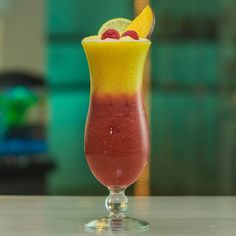 a glass filled with liquid and topped with a fruit garnish on top of a table