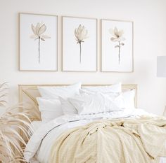 a bed with white sheets and pillows in a bedroom next to two framed pictures on the wall